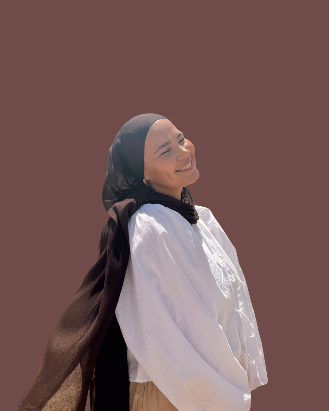 Iman Meskini smiling in a black hijab and white shirt